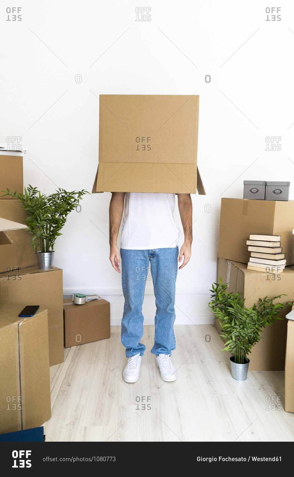 Man covering head with cardboard box while standing in new house