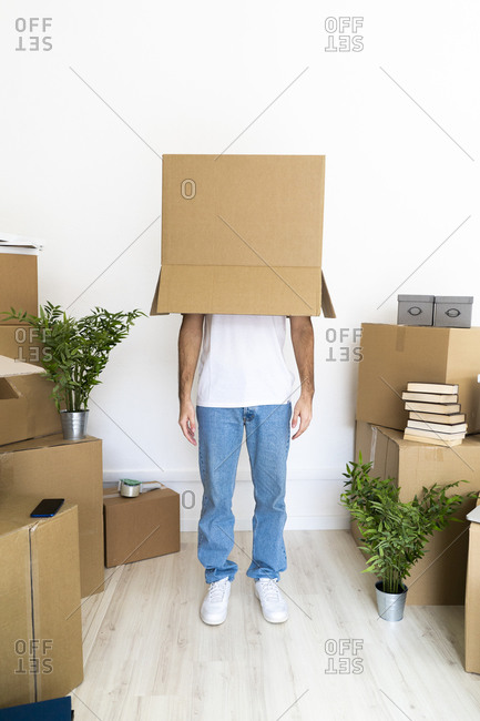 Man covering head with cardboard box while standing in new house