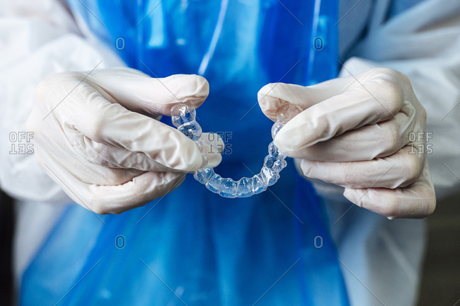 Doctor holding transparent dental aligner while standing at clinic
