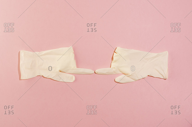 Studio shot of pair of surgical gloves touching with index fingers