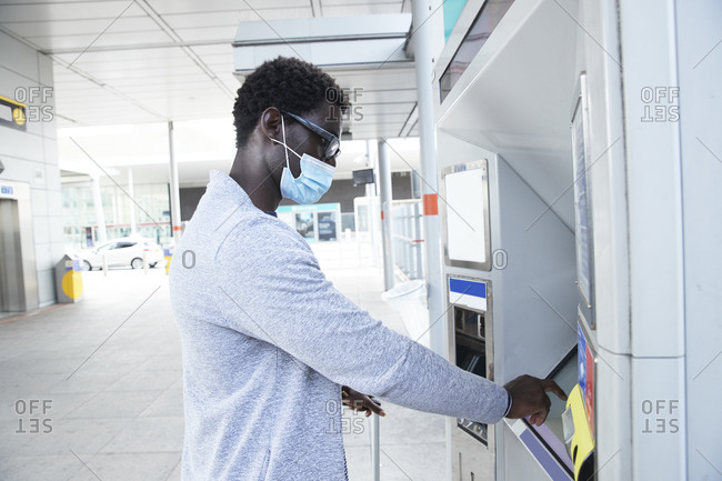 Mature male professional using ticket machine at railroad station during coronavirus