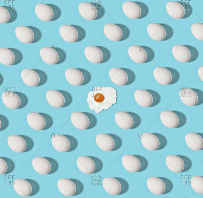 Pattern of white chicken eggs and single fried one