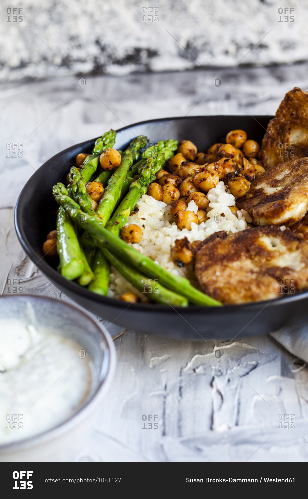 Dipping sauce and bowl of rice with chick-peas- asparagus stalks and fried halloumi cheese