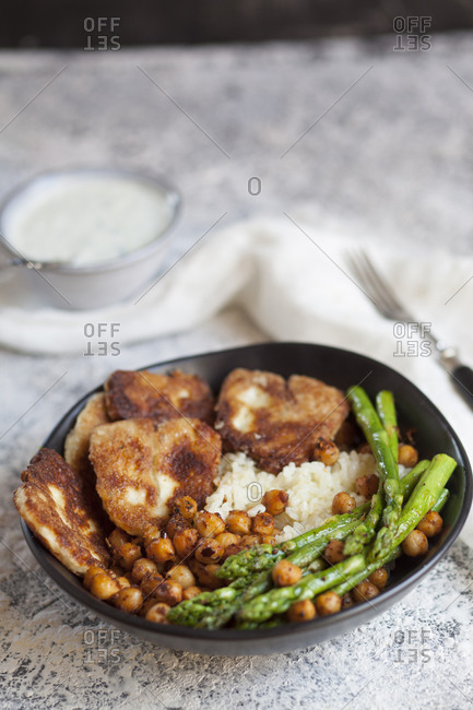 Dipping sauce and bowl of rice with chick-peas- asparagus stalks and fried halloumi cheese