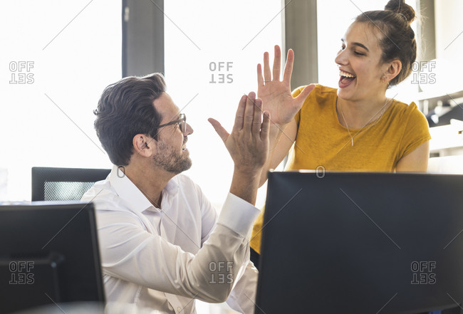Business people giving high five while working together st office