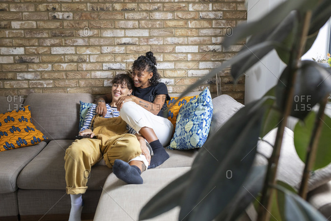 Happy Mixed Race Couple Relax On Couch In Living Room Watch Movie