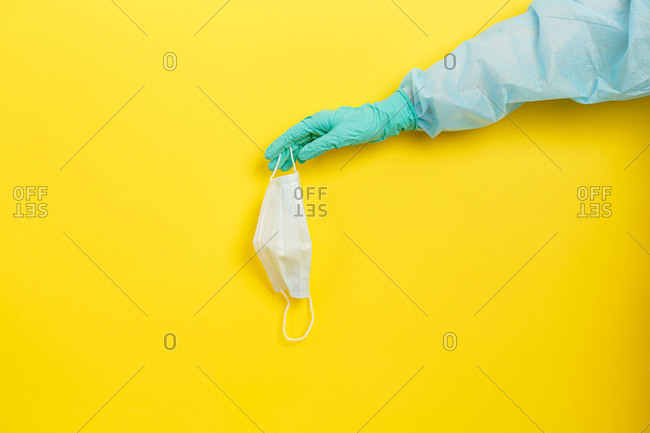Hand of a medical officer in protective coverall with a protective mask in hand