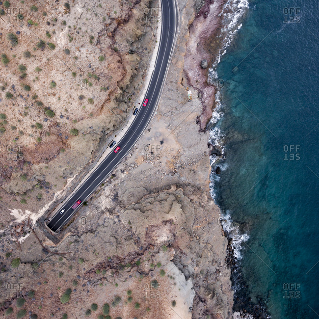 Road leading through a tunnel under the mountain by the ocean from above