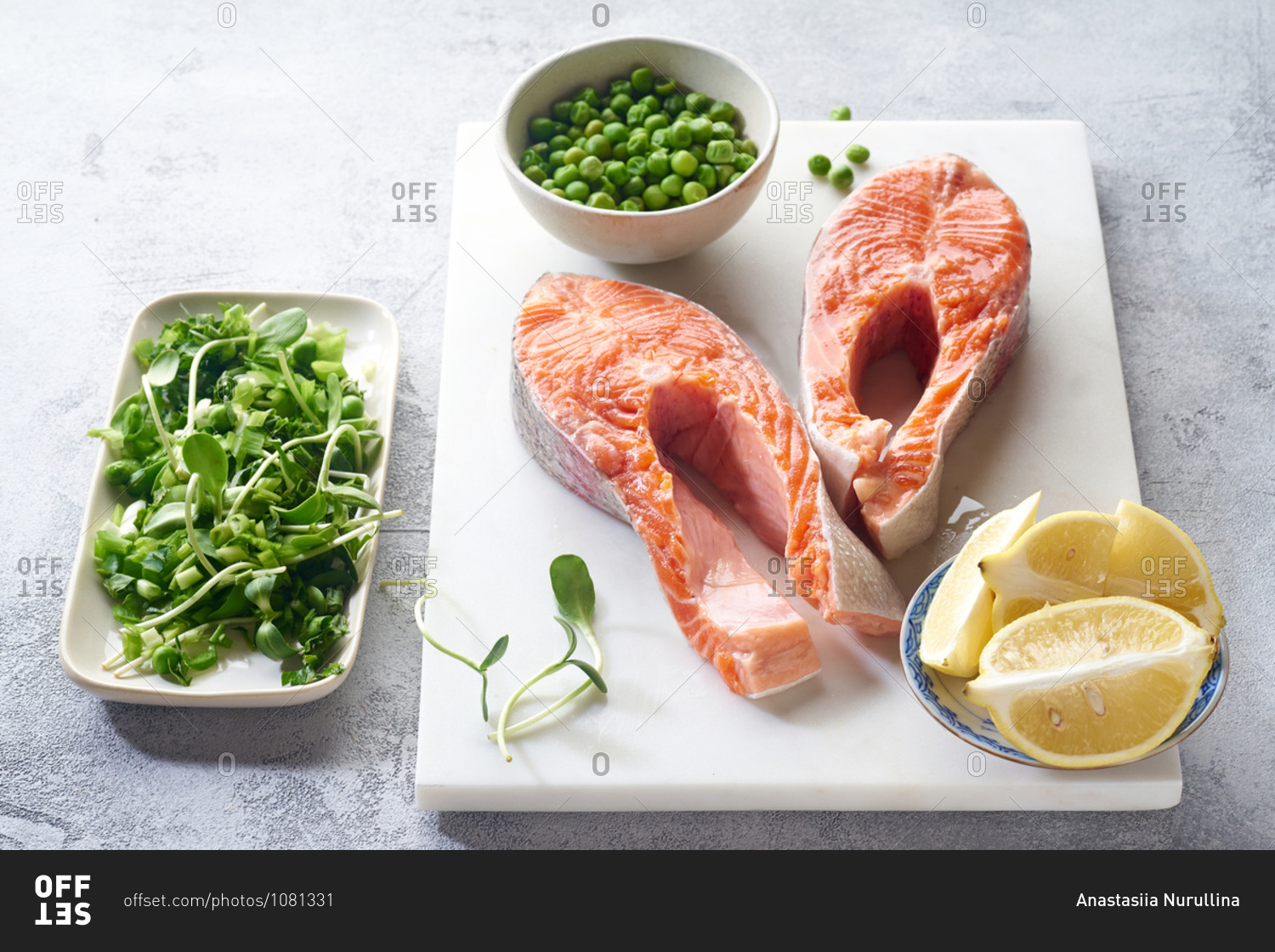 Raw salmon steak top view with micro greens, lemon and green peas. Ingredients for cooking healthy dinner.