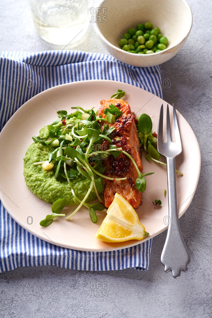 Cooked dinner with roasted salmon, mashed peas and sunflower green sprouts