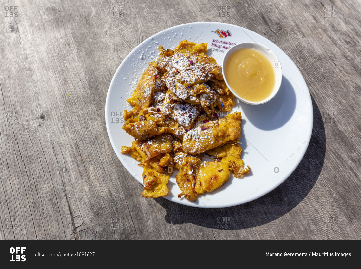 Traditional dessert  Kaiserschmarrn with Pear sauce and powered sugar, close-up on a wooden table, Dolomites, South Tyrol, Bolzano, Italy