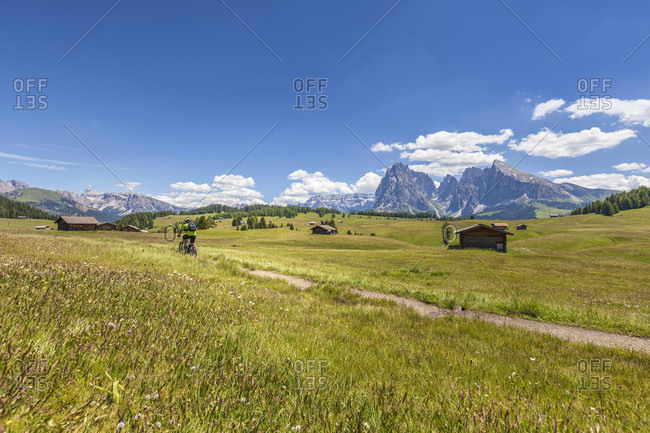 Cyclist with an electric mountain bike (e-bike) pedaling in Alpe di Siusi, Seiseralm, South Tyrol, Dolomites, Italy