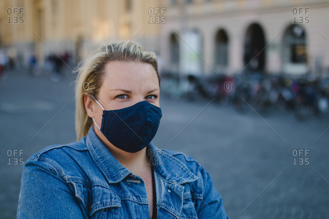 Blond woman with mask in Corona times on full Odeonsplatz in Munich
