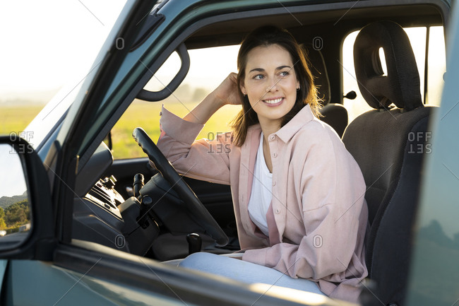 Smiling young woman looking away while sitting in car during road trip