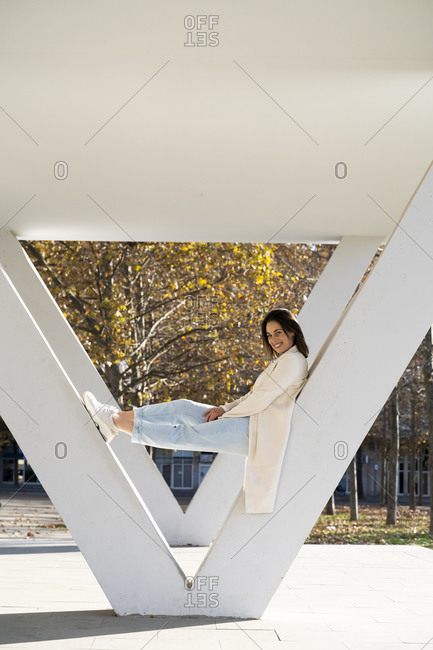 Smiling businesswoman relaxing on column in park