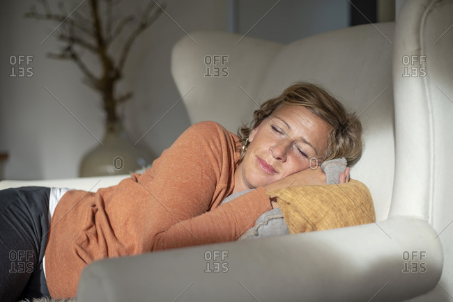 Mature woman napping while lying on sofa at home