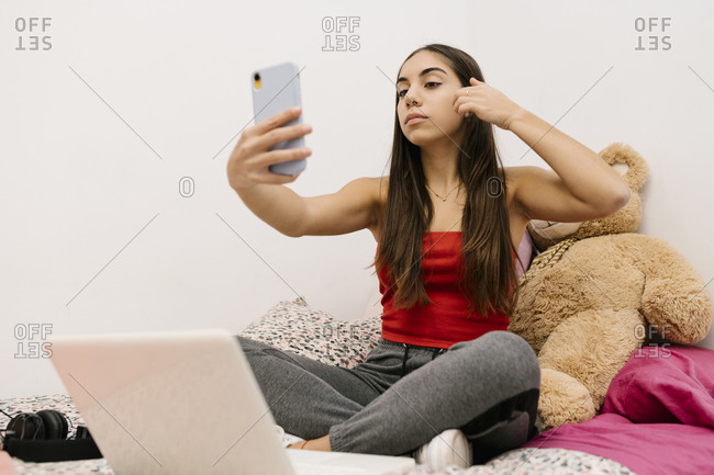Teenage girl sitting with hand in hair while using mobile phone sitting at home