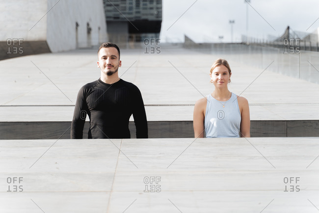 Couple in sports clothing standing by retaining wall