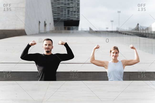 Athletes showing muscles while standing by retaining wall