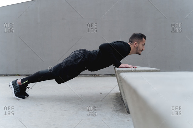 Male athlete doing push-up while exercising against wall