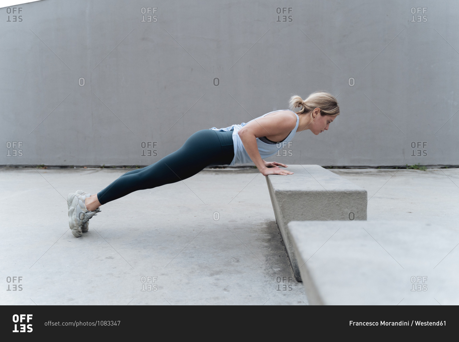 Sportswoman doing push-ups while exercising against wall