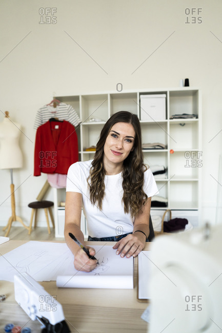 Smiling female creative professional sitting with drawing book at studio