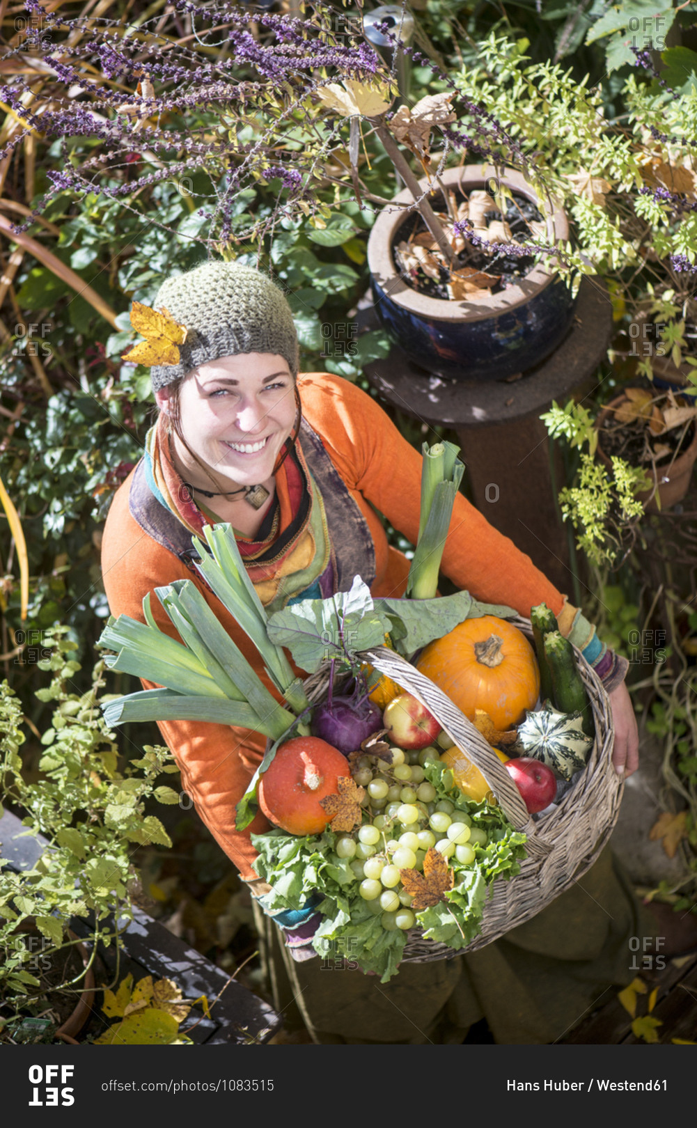 Smiling woman carrying fruit and vegetable basket while standing in garden