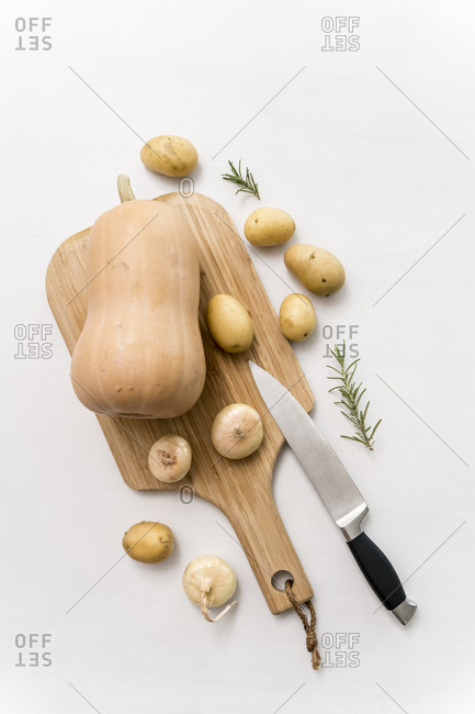 Studio shot of pumpkin- raw potatoes and onions on cutting board