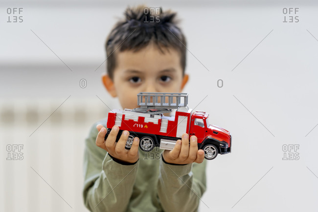 Cute boy holding fire engine toy at home
