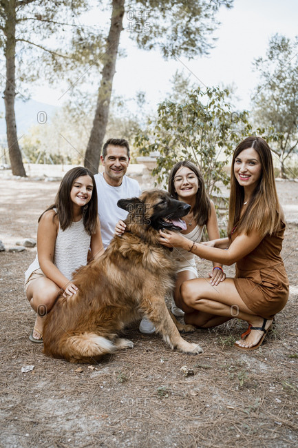 Smiling parents and children with dog in park during vacation
