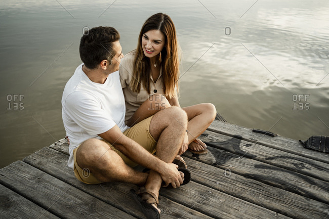Couple sitting against lake at jetty