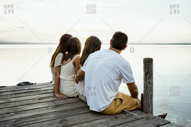 Family admiring lake while sitting at jetty