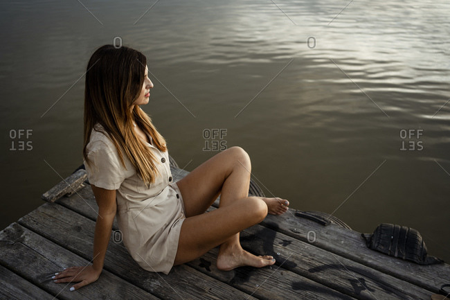 Mature woman sitting at jetty in front of lake
