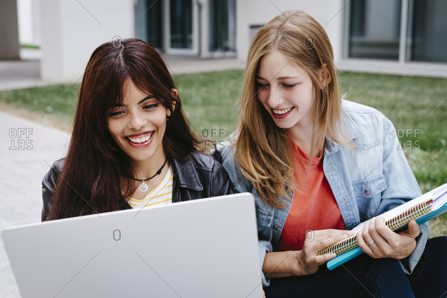 Smiling young multi-ethnic female students using laptop at campus