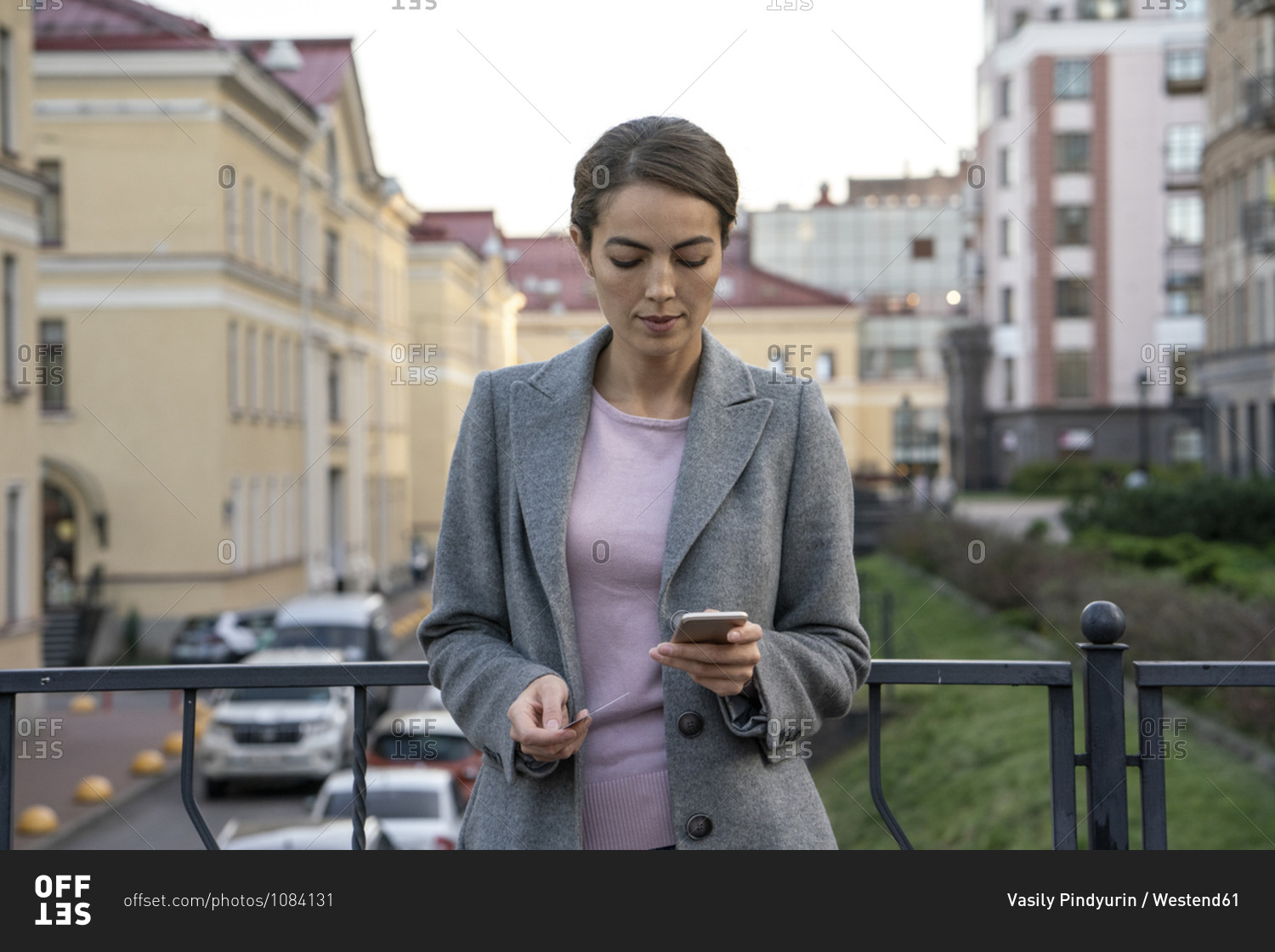 Female entrepreneur holding credit card while making payment through smart phone in city