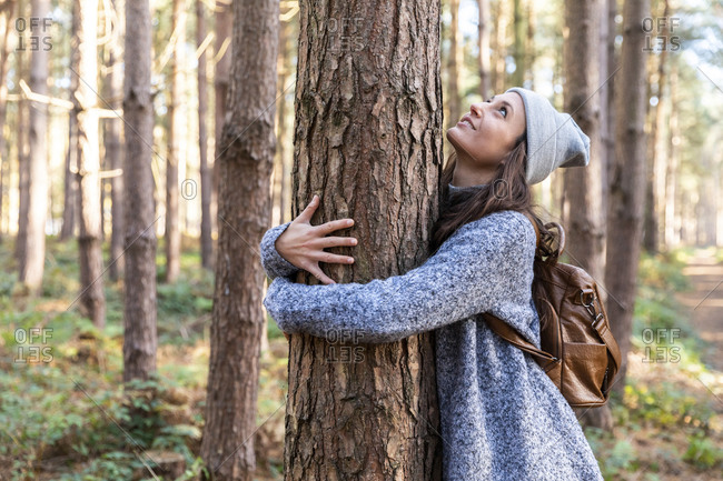 Female hiker embracing tree trunk while exploring in Cannock Chase woodland