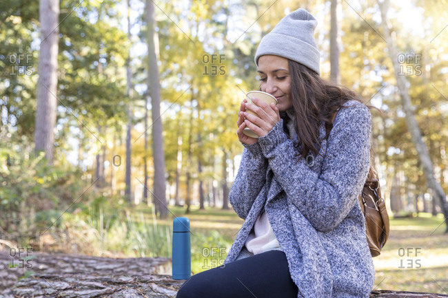 Female hiker smelling tea while sitting in Cannock Chase forest