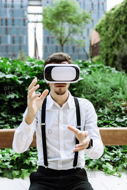 Businessman wearing virtual reality goggles outdoors
