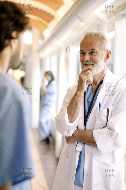 Male nurse talking to smiling wrinkled expert in hospital