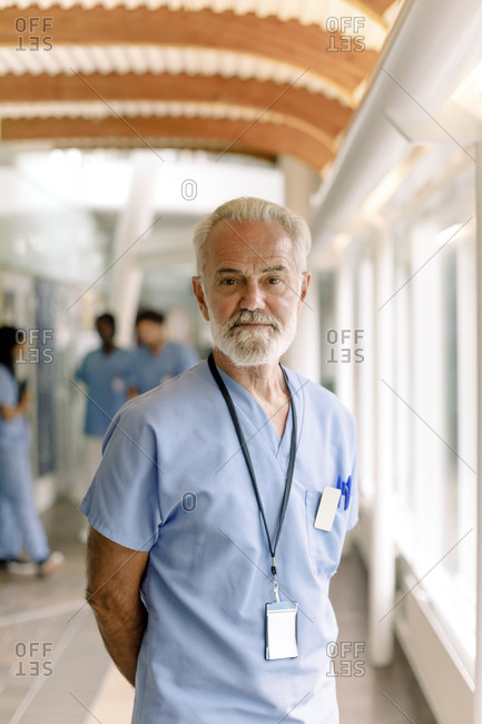 Portrait of wrinkled male nurse standing in hospital corridor