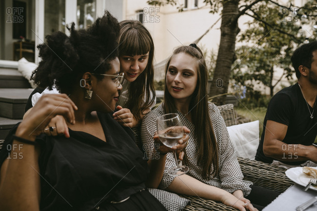 Smiling female friends talking while enjoying during garden party