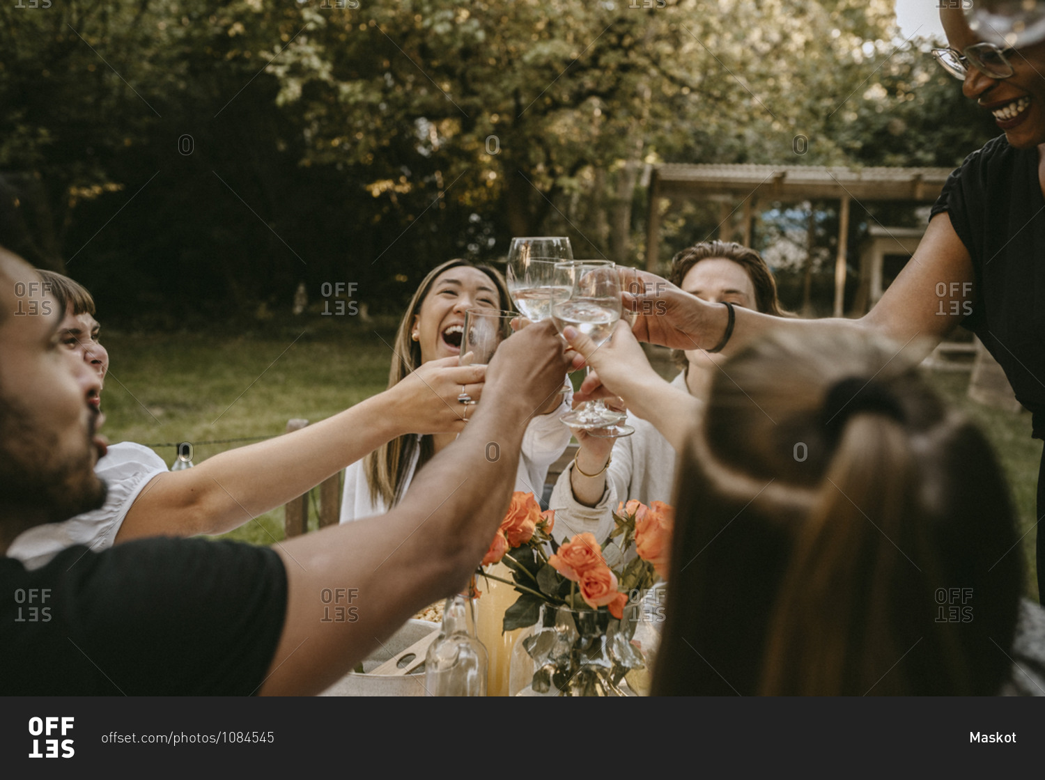 Cheerful young woman toasting drinks with friends during social gathering
