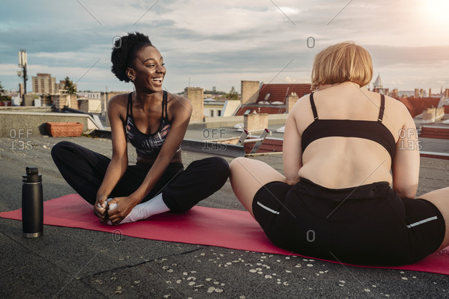 Smiling female friends exercising on rooftop
