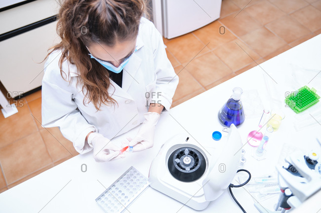 Top view of a young female scientist working in a laboratory sampling DNA in a test tube with a centrifuge. Laboratory research concept.