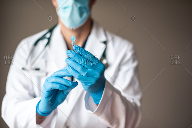 Doctor in white coat holding syringe with vaccine ready for injection.
