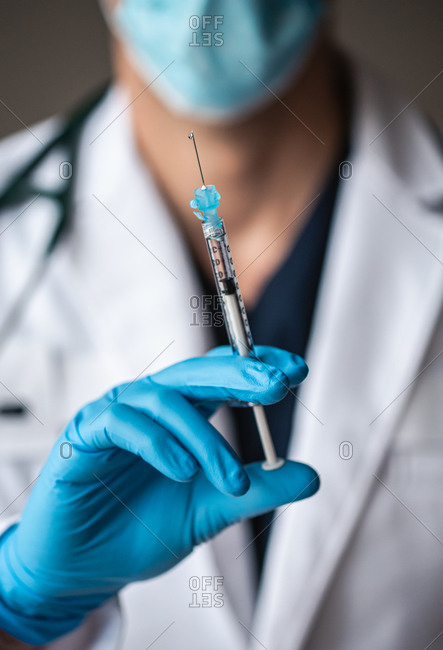 Close up of doctor holding needle with vaccine ready to inject.