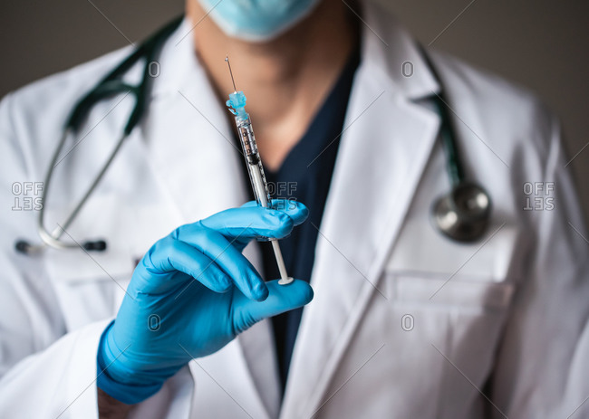 Doctor in white coat holding syringe with vaccine ready for injection.