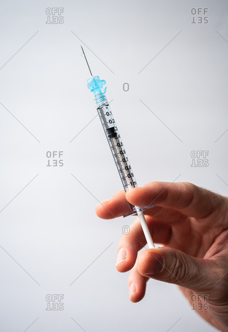 Close up of hand holding a syringe with a vaccine on white background.