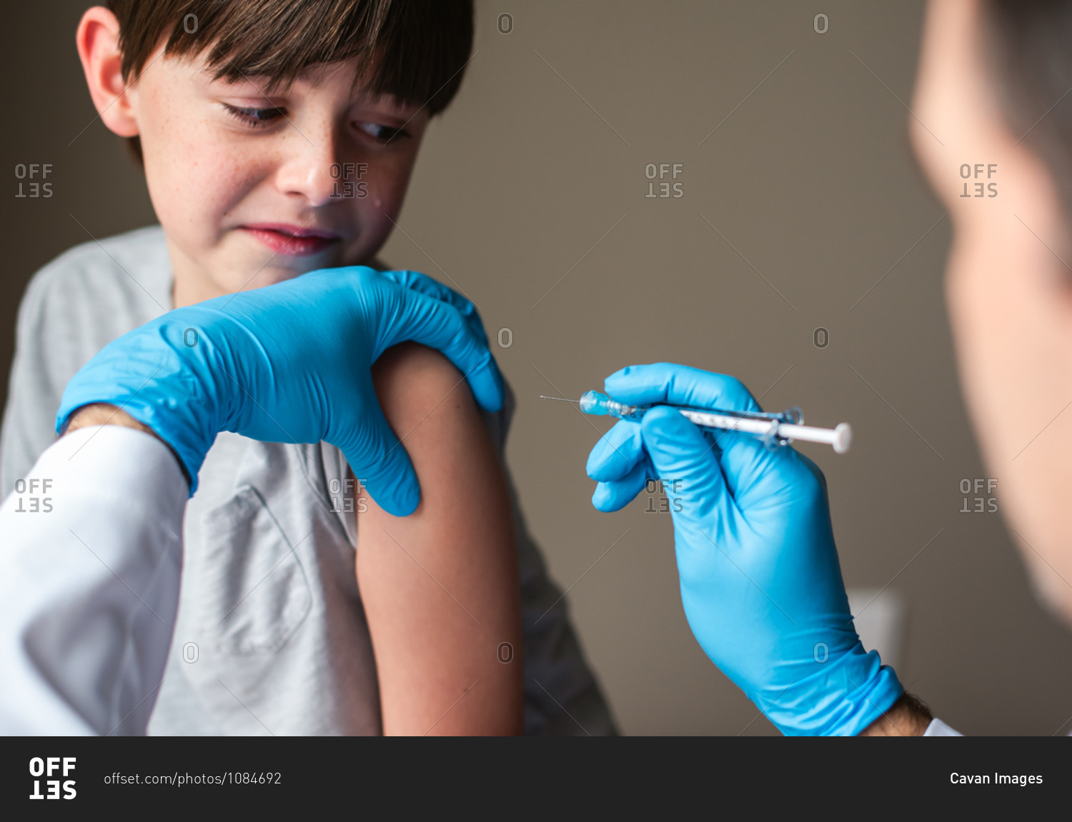 Nervous looking child getting vaccinated by doctor holding a needle.