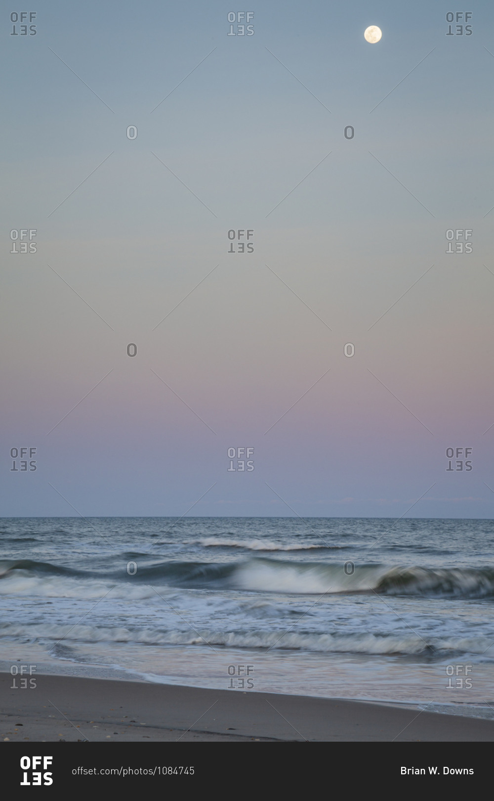 Full moon setting over crashing waves at dawn on Cape Lookout National Seashore, North Core Banks, North Carolina